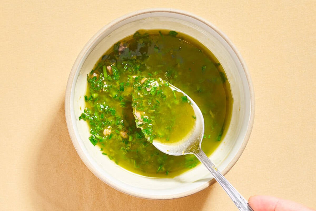 The dressing for the italian gren bean salad in a bowl with a spoon.