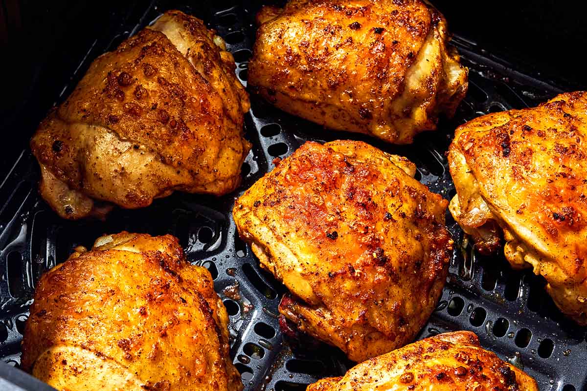 Six air fryer chicken thighs in an air fryer.